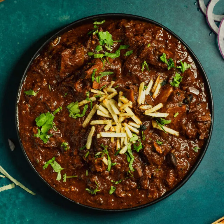 Goat curry garnished with ginger and cilantro
