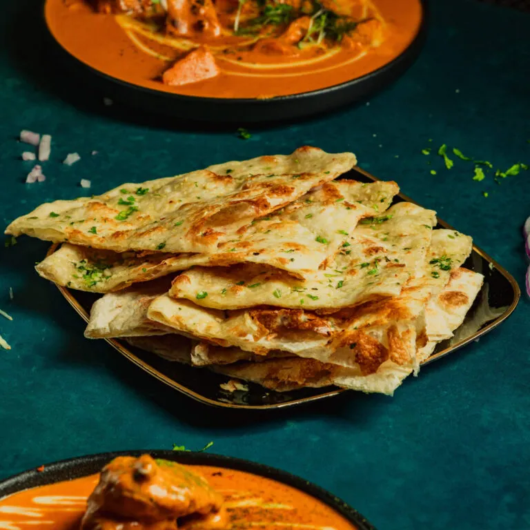 Garlic naan stacked beside butter chicken